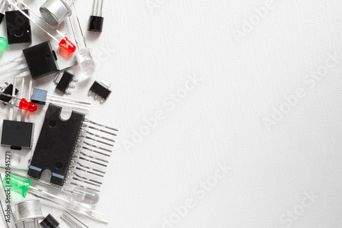 Electronic components over white background with copy space. There are transistors, red and green LEDs, microcircuits.