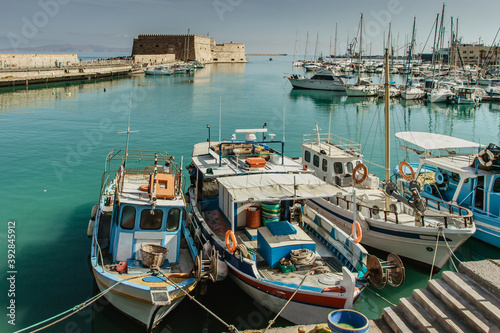 Old port with fishing boats and Venetian fortress of Koules,Castello a Mare in Heraklion, Crete.Panoramic view of the old harbour and turquoise clear water.Travel background copy space.