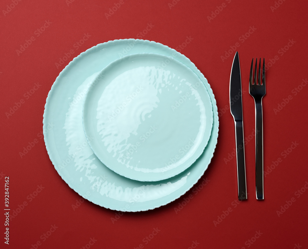 round ceramic plates, fork with knife on a red background
