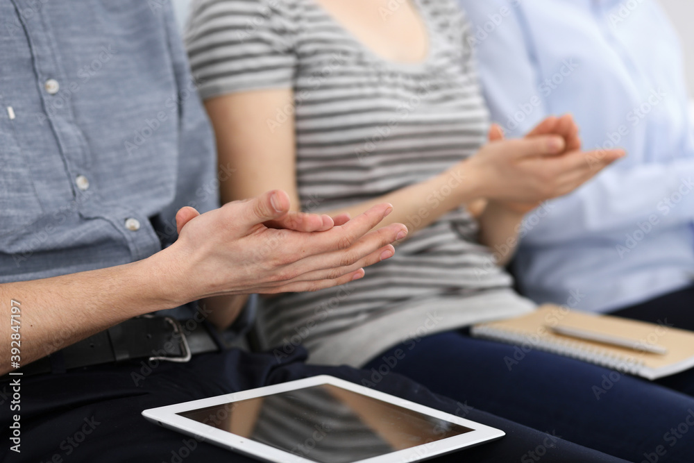 Fototapeta premium Business people clapping at meeting or conference, close-up of hands. Group of unknown businessmen and women in modern white office. Success teamwork, corporate coaching and applause concept