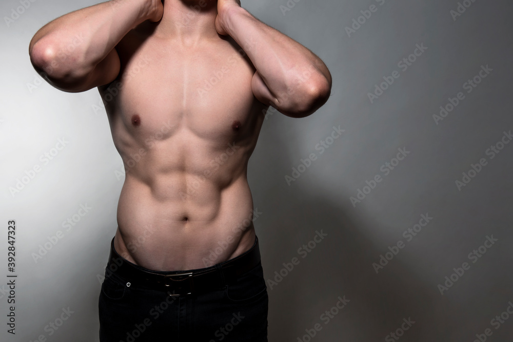 Muscular and fit bodybuilder shirtless on grey background