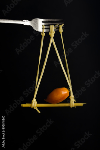Spaghetti on a fork in front of black background. Swing from spaghetti