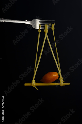 Spaghetti on a fork in front of black background. Swing from spaghetti