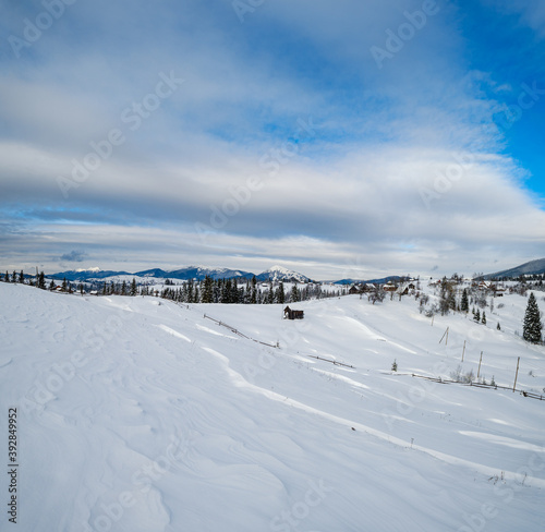 Countryside hills, groves and farmlands in winter remote alpine mountain village © wildman