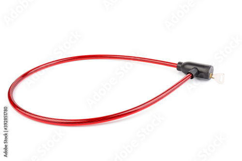 Flexible red bicycle cable with key on white background. Security and safety concept.