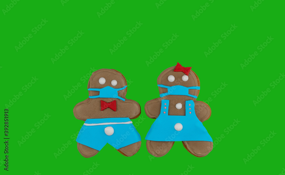 pair of gingerbread cookies on a green background. little men in medical masks.cookies made with your own hands. top view, copy space