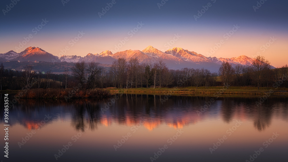 autumn pond with the reflection of the mountains on the surface at sunset