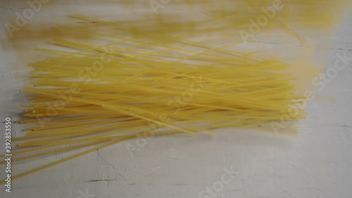 Raw spaghetti falling on table. Slow motion