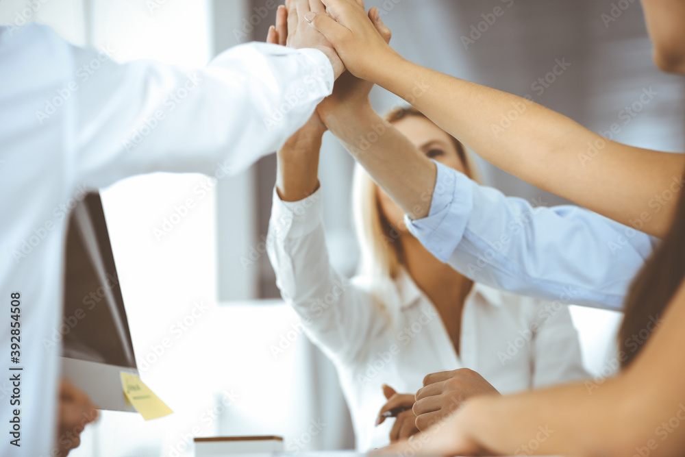 Group of business people joining hands or giving five to each other after meeting or negotiation in modern office. Colleagues showing teamwork, cooperation and partnership in corporate occupation Group of business people joining hands or giving five to each other after meeting or negotiation in modern office. Colleagues showing teamwork, cooperation and partnership in corporate occupation
