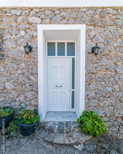 white door and stone wall house by the sidewalk