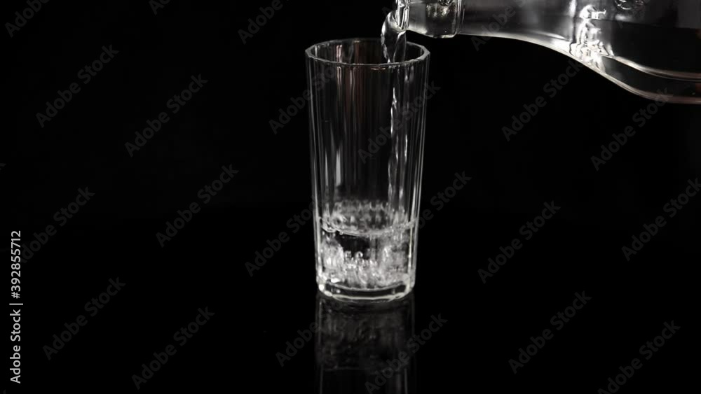 Filling a glass with water. Glass of water on a black background. Person filling up a glass with water. Filling a glass with water. Glass of water on a black background. Person filling up a glass with water.
