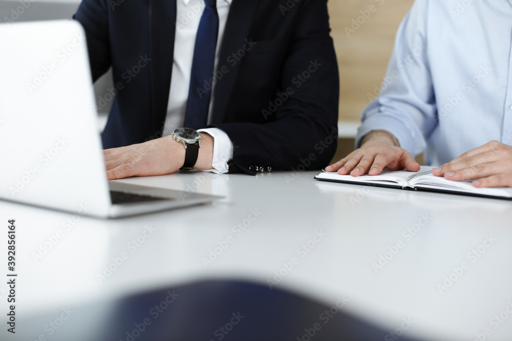 Unknown business people using laptop computer at the desk in modern office. Businessman or male entrepreneur is working with his colleague. Teamwork and partnership concept Unknown business people using laptop computer at the desk in modern office. Businessman or male entrepreneur is working with his colleague. Teamwork and partnership concept
