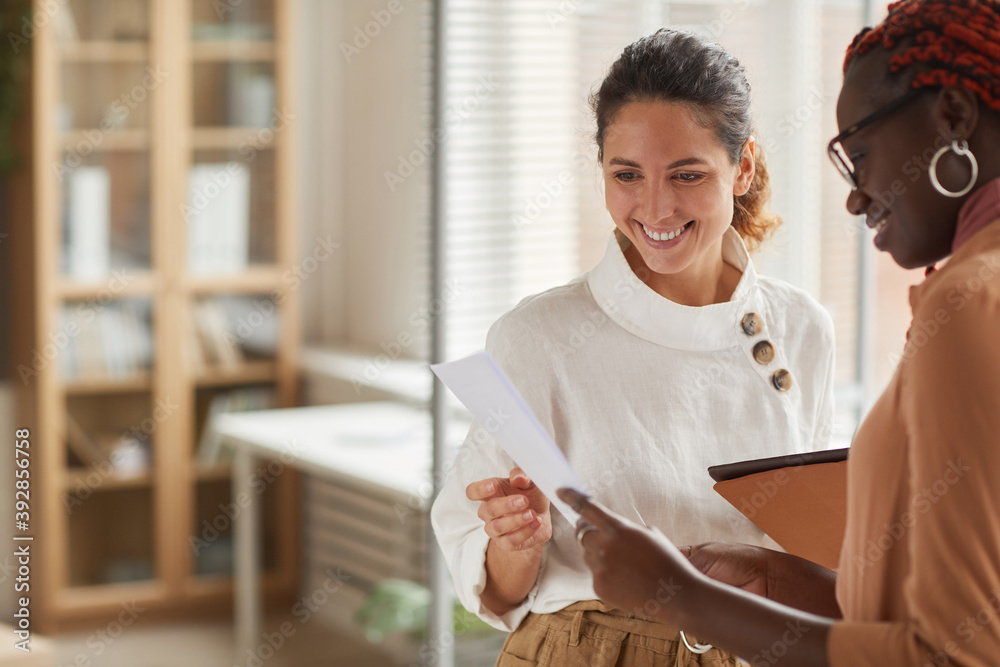 © Seventyfour - Waist up portrait of modern successful businesswoman talking to female intern and smiling cheerfully while standing in office interior, copy space © Seventyfour - Waist up portrait of modern successful businesswoman talking to female intern and smiling cheerfully while standing in office interior, copy space