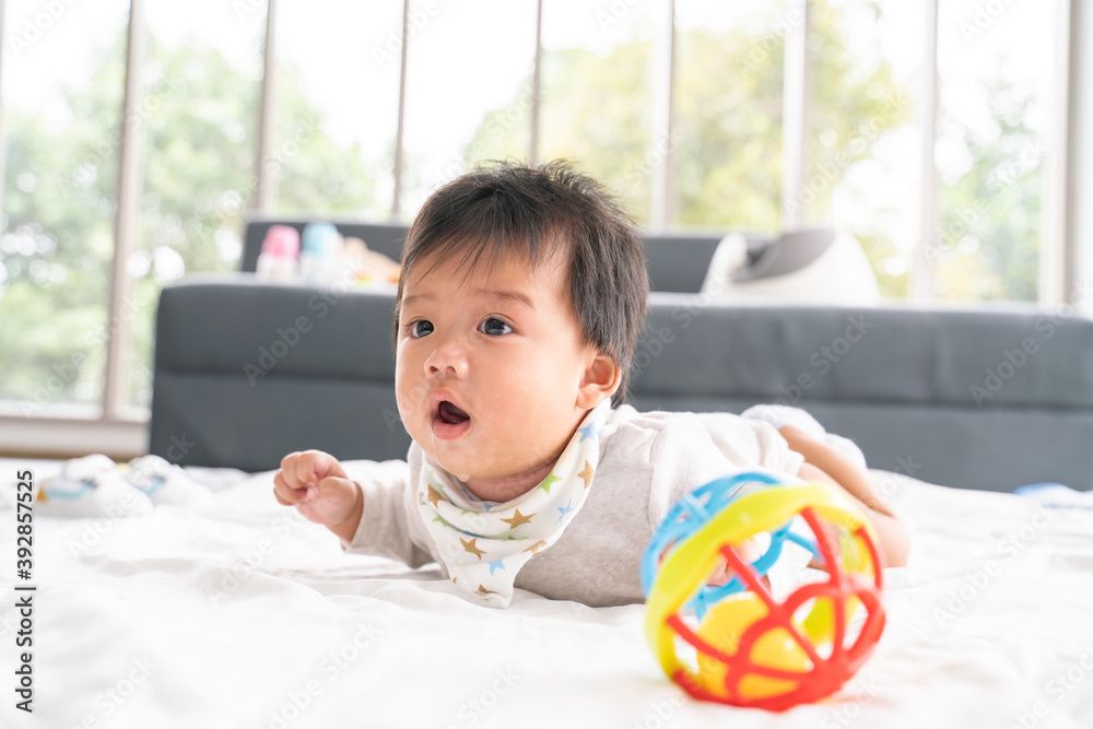Close up portrait view of Young cute Asian baby crawling on bed in bedroom.The newborn baby or kid smiling at the right with joyfulness and happiness at home.baby health care concept,copy space. Close up portrait view of Young cute Asian baby crawling on bed in bedroom.The newborn baby or kid smiling at the right with joyfulness and happiness at home.baby health care concept,copy space.