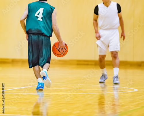体育館でバスケットボールをする学生