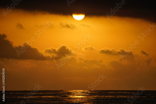 Beautiful golden beach sunrise on the Mediterranean coast with sun reflection. Clouds. Golden hour.