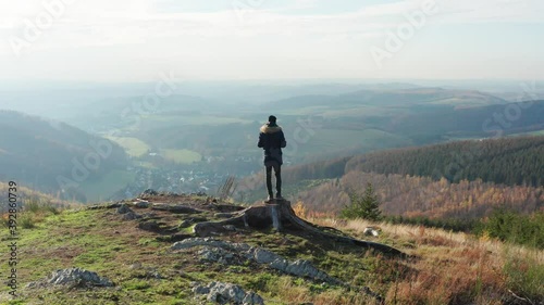 
a man is standing on a hill above a low mountain range filmed in 4k with movement
 photo