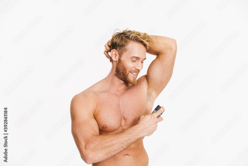 Happy caucasian shirtless man smiling while using deodorant