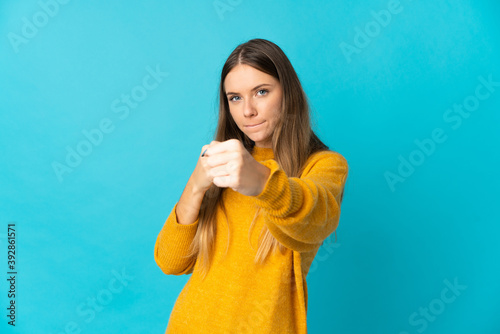 Young Lithuanian woman isolated on blue background with fighting gesture © luismolinero