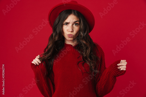 Unhappy beautiful brunette girl in hat posing and looking at camera