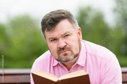 Serious adult man is reading a book. Large portrait.