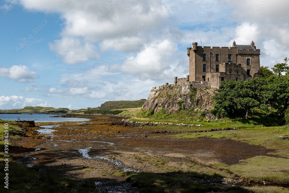 Dunvegan Castle on a top a hill at Isle of Skye, Scotland during the low tide with blue sky