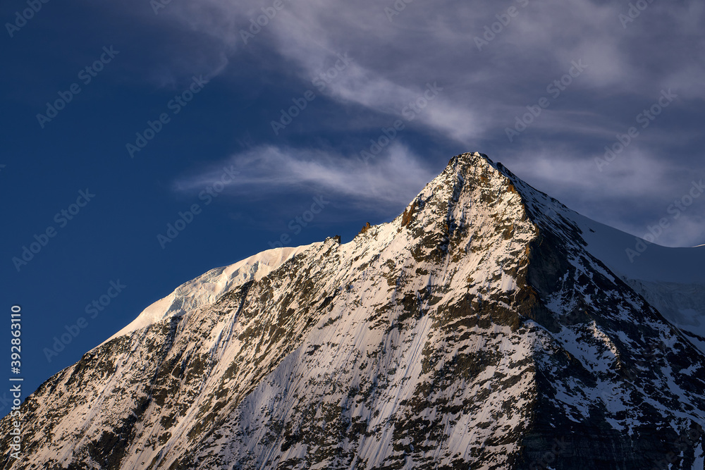 pyramidenförmiger Bergmassiv in der Abendsonne mit viel Wind an der Spitze