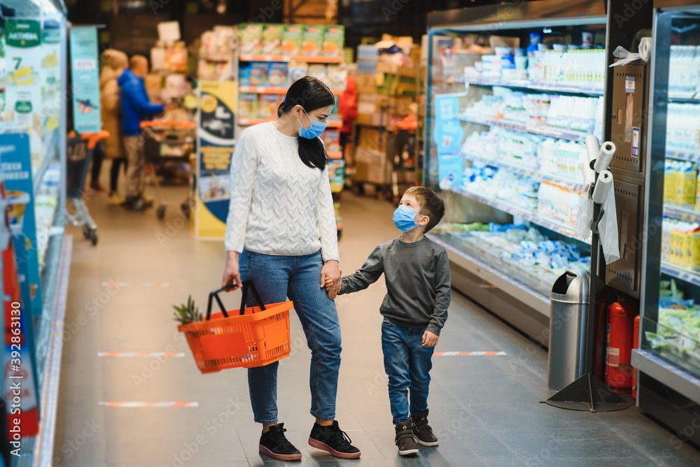Obraz premium Mother and son are shopping at the grocery store. They wear masks during quarantine. Coronavirus Pandemic .COVED-19 Flash. The epidemic of the virus
