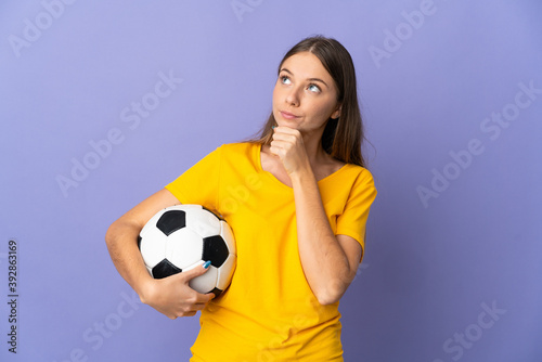 Young Lithuanian football player woman isolated on purple background and looking up © luismolinero