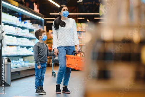 Young woman and her kid wearing protective face masks shop a food at a supermarket during the coronavirus epidemic or flu outbreak © Serhii