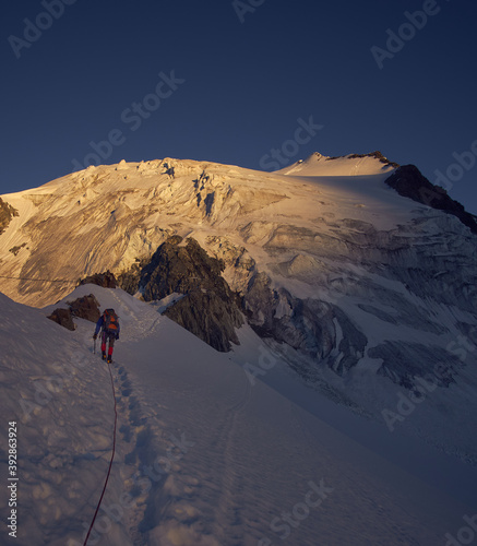 mountaineer on a rope going toward the distant peak while the sun is rising photo