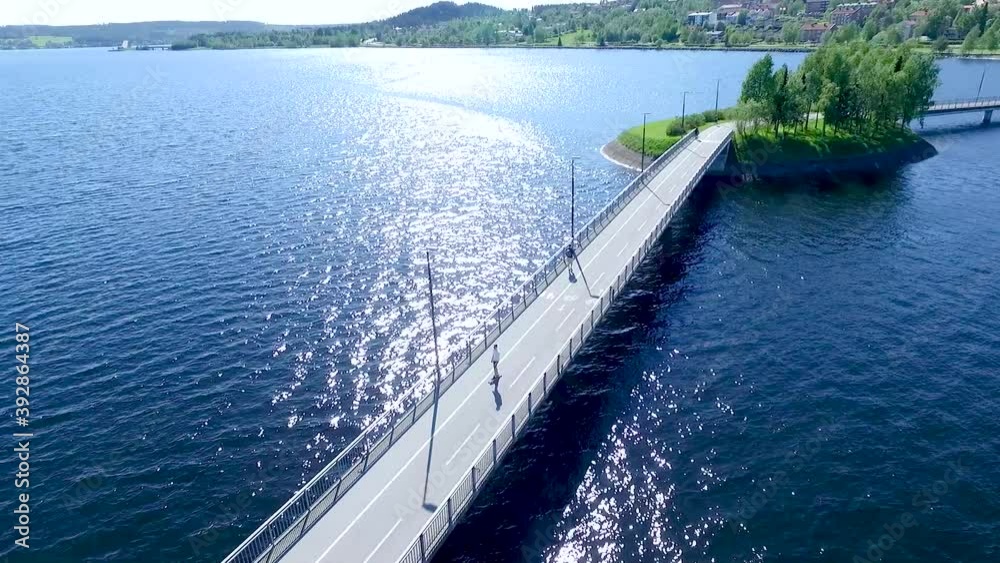 drone shot over lake following a skateboarder over a bridge. drone shot over lake following a skateboarder over a bridge.