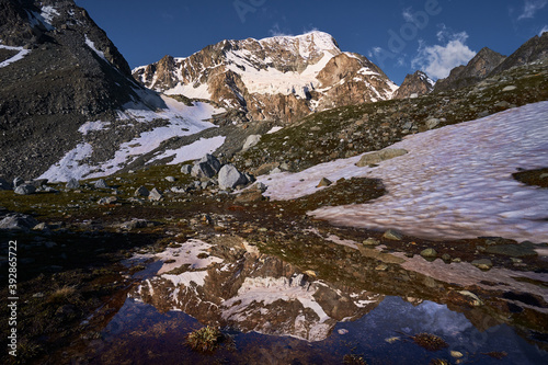 reflection of Pigne d`Arolla mountain peak in a small high alpine lake. Arolla valley, Switzerland