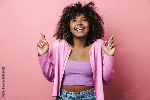 Excited african american woman posing with fingers crossed for good luck