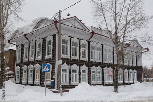 Russian snow winter. Carved windows, frames on vintage wooden house on Shishkov street, 1, Tomsk city, Russia. Cold season. Russian style in architecture. Tomsk architecture landmark. Snowdrifts photo