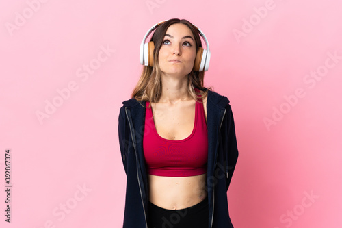 Young Romanian sport woman isolated on pink background and looking up