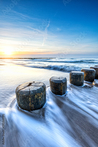 Fototapeta Naklejka Na Ścianę i Meble -  Buhne aus Holz an der Ostseeküste zum Sonnenuntergang