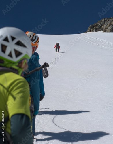 Fényképezés Mountaineers looking at their friend who is climbing up a snow covered steep hil
