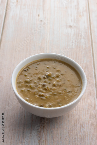 Mung beans porridge (bubur kacang hijau) is a Malaysian traditional dish usually eat as starter or desert. Made from mung beans, coconut milk & palm sugar. Isolated over wooden background.