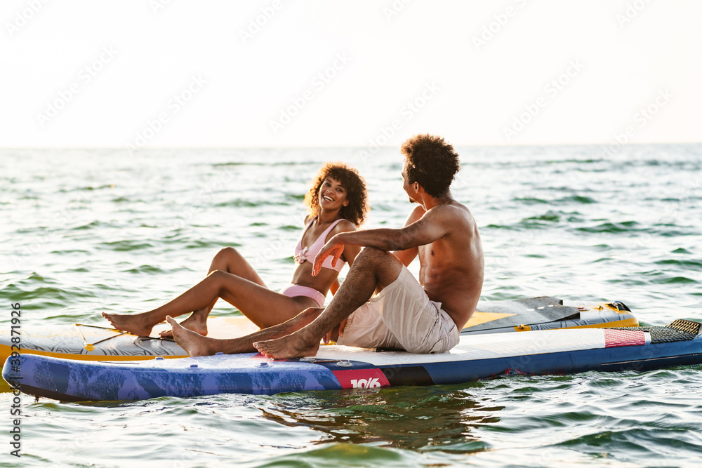 Obraz premium Young african couple talking on paddle boards