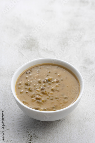 Mung beans porridge (bubur kacang hijau) is a Malaysian traditional dish usually eat as starter or desert. Made from mung beans, coconut milk & palm sugar. Isolated over wooden background.
