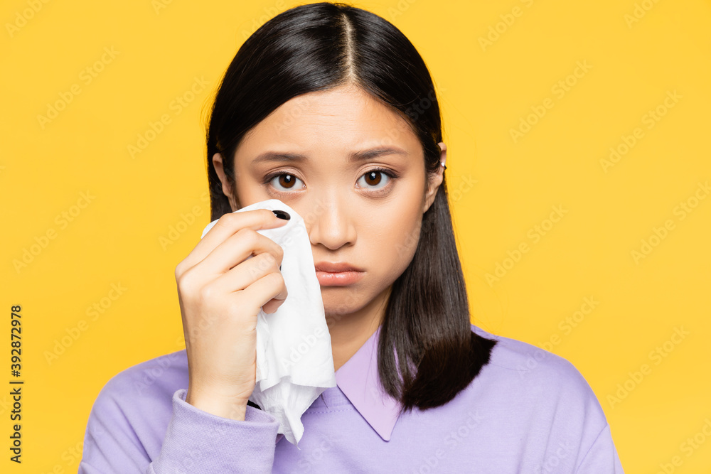 sad asian woman holding napkin while crying isolated on yellow sad asian woman holding napkin while crying isolated on yellow