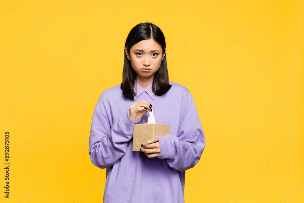 sad asian woman holding tissue box isolated on yellow sad asian woman holding tissue box isolated on yellow