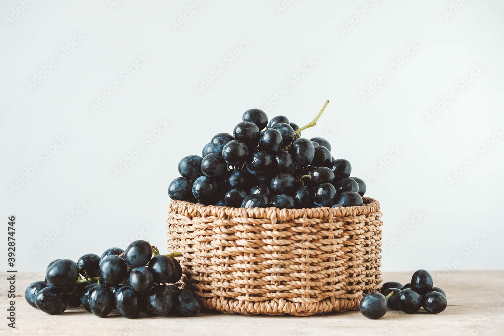 Bunch of black grapes in a round wicker basket on a old wooden table. Copy, empty space for text Bunch of black grapes in a round wicker basket on a old wooden table. Copy, empty space for text