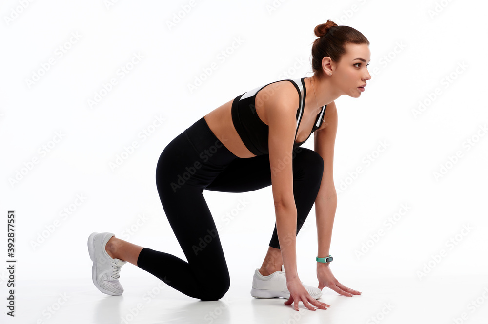 Side profile view of concentrated powerful focused strong woman standing at start line, she is ready to run the distance, isolated on white background