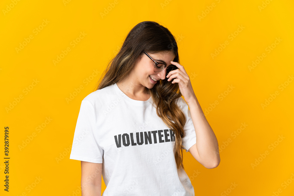 Young volunteer woman isolated on yellow background laughing Young volunteer woman isolated on yellow background laughing