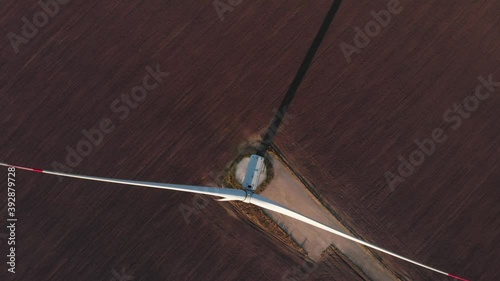 Top view rotating high wind turbine power plant aerial sunset view long shadow. Windmill generating renewable energy drone shot 4K