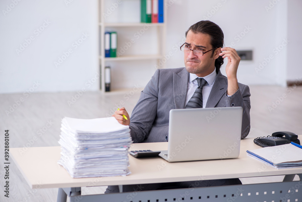 Young male employee unhappy with excessive work in the office Young male employee unhappy with excessive work in the office