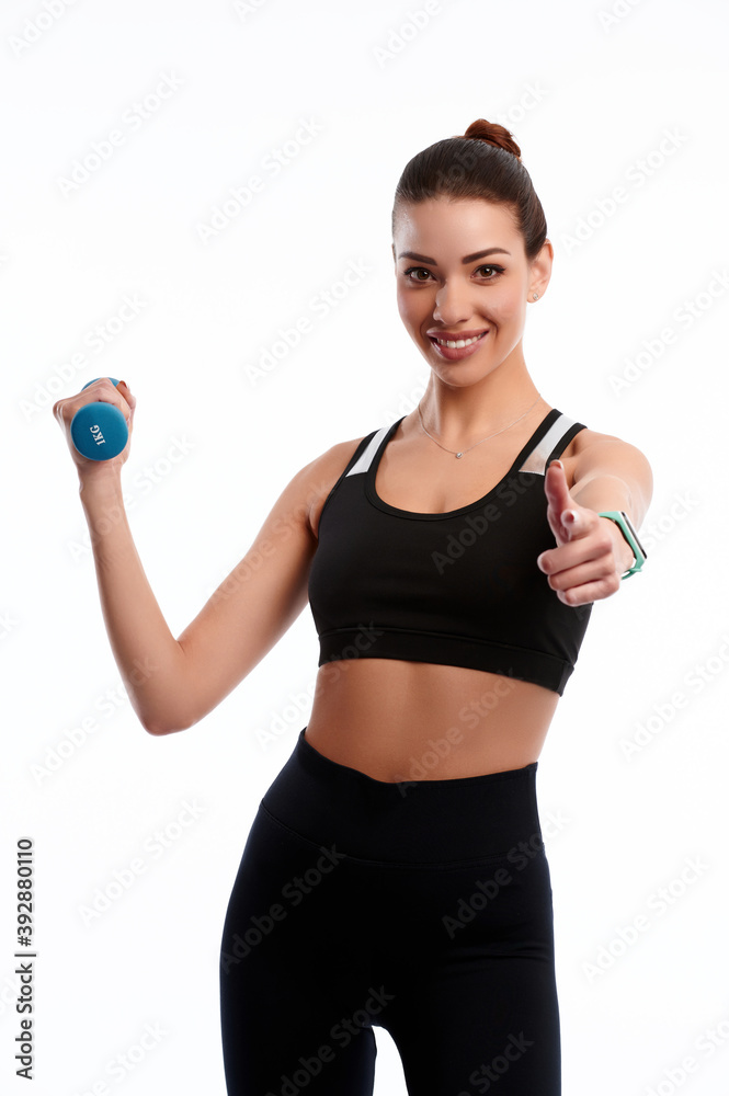 Attractive caucasian slim woman doing physical exercise using dumbbell and showing finger gesture isolated on white background Attractive caucasian slim woman doing physical exercise using dumbbell and showing finger gesture isolated on white background
