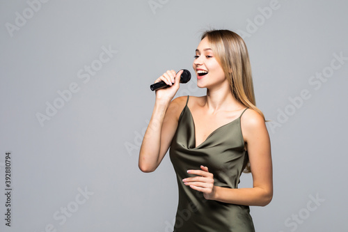Beautiful young woman with microphone on grey background